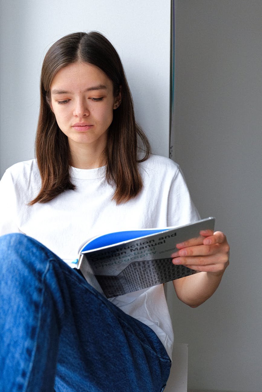 woman in white crew neck t shirt holding a book